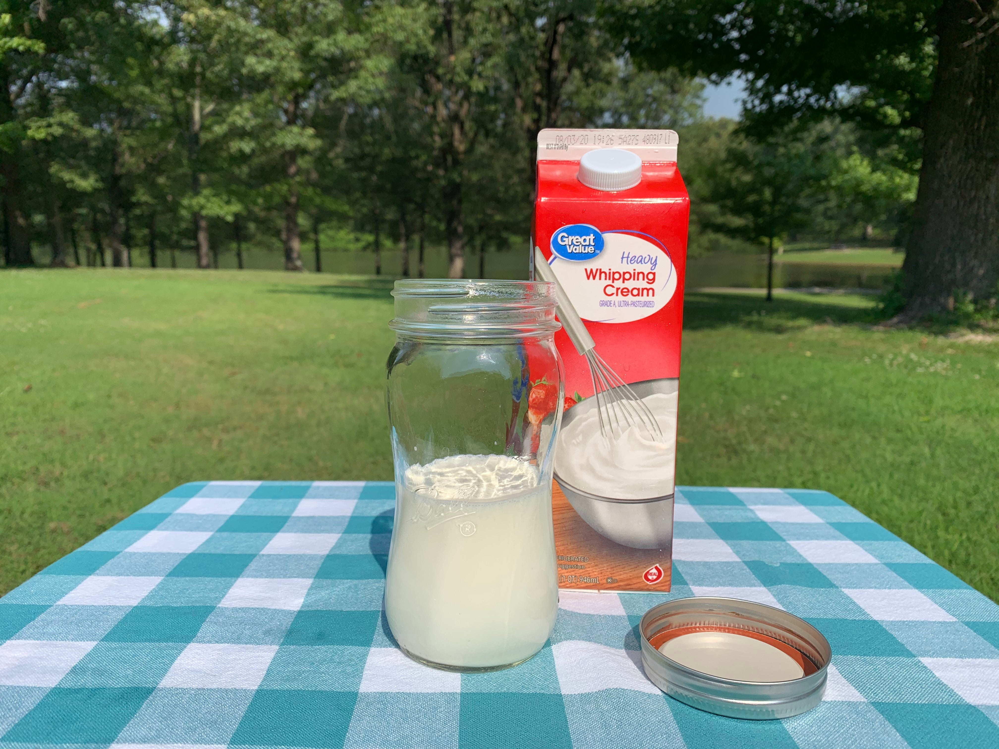 On the table there is a mason jar that is filled halfway with cream.)